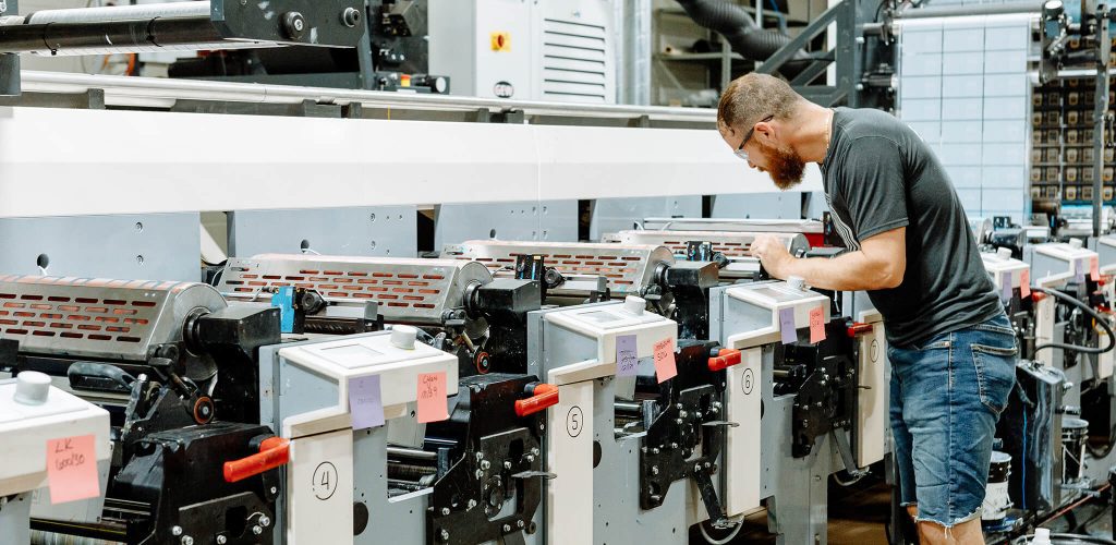 Press operator assessing a flexographic press being used to print custom pressure sensitive and shrink sleeve labels at Steinhauser.