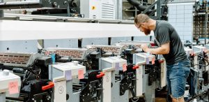 Press operator assessing a flexographic press being used to print custom pressure sensitive and shrink sleeve labels at Steinhauser.