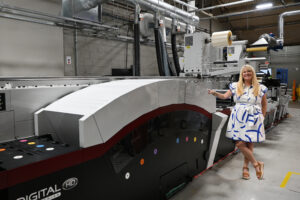 CEO and Owner of Steinhauser, Inc., Tara Halpin, standing beside the company's newest investment, the Mark Andy Digital Series HD, their introduction to hybrid printing.