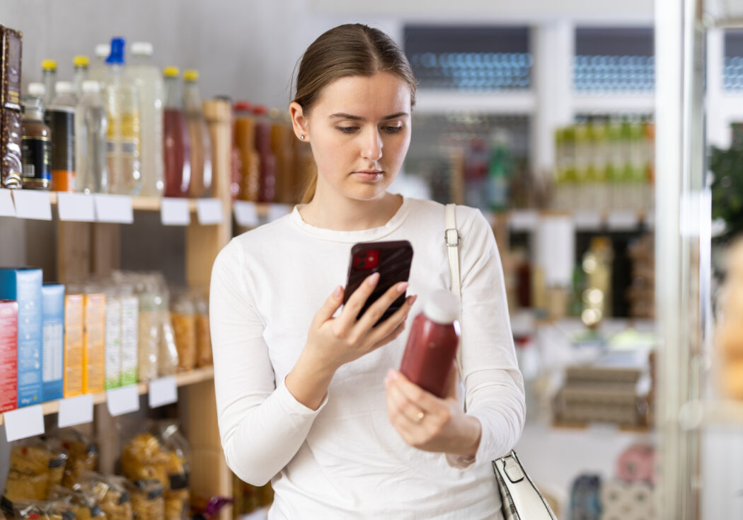 Woman scanning QR code on CPG packaging at the grocery store